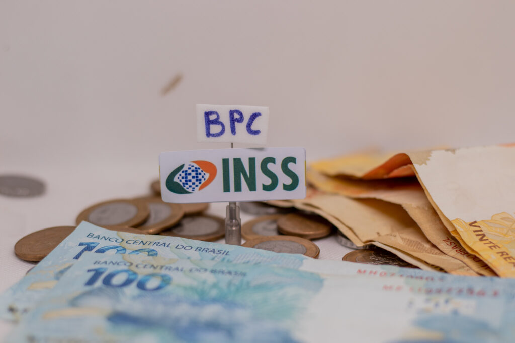 imagem de notas de reais com símbolo do INSS e papel escrito BPC